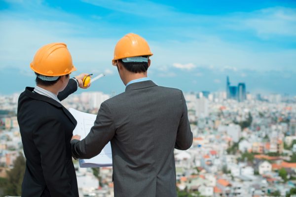 Businessmen in hardhats taking a look at the blueprint in urban environment